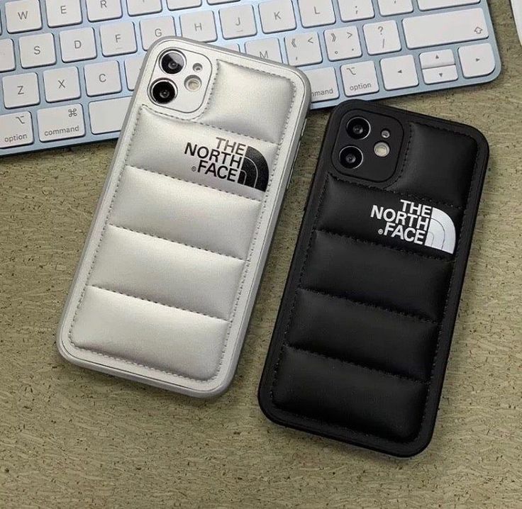 two cell phones sitting next to each other on a desk with keyboard and phone case