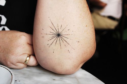 a woman's arm with a tattoo on it and a starburst in the middle