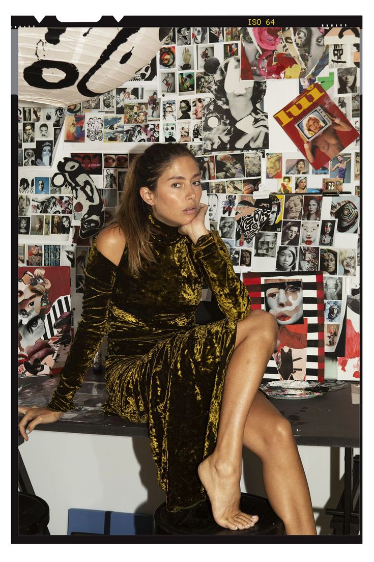 a woman sitting on top of a table next to a wall covered in pictures