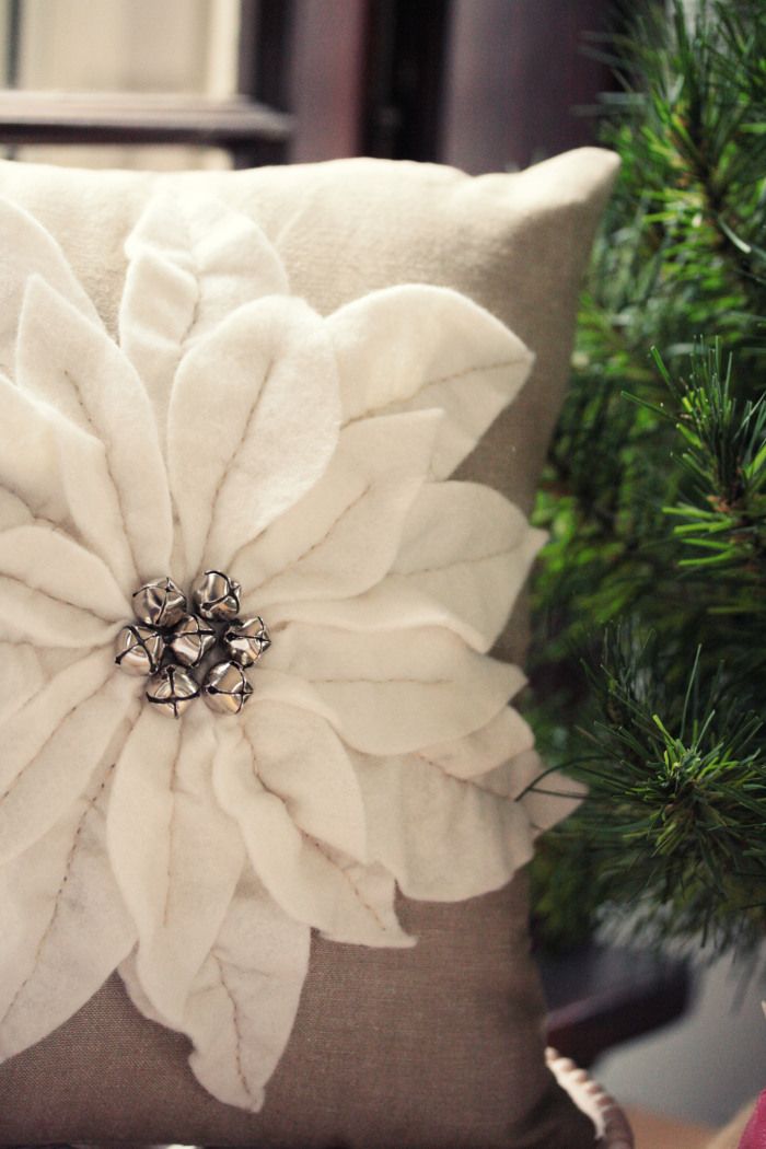 a pillow with a flower on it sitting next to a christmas tree in front of a window