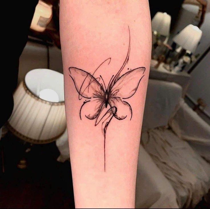 a black and white photo of a butterfly tattoo on the right arm, with lines drawn across it