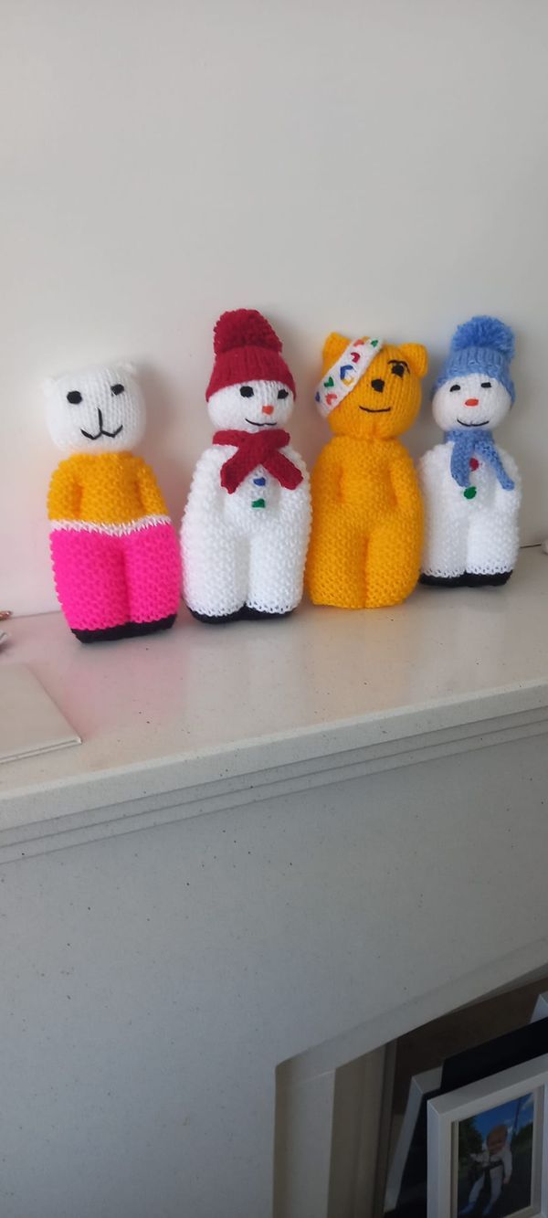 four knitted stuffed animals sitting on top of a white shelf next to a wall