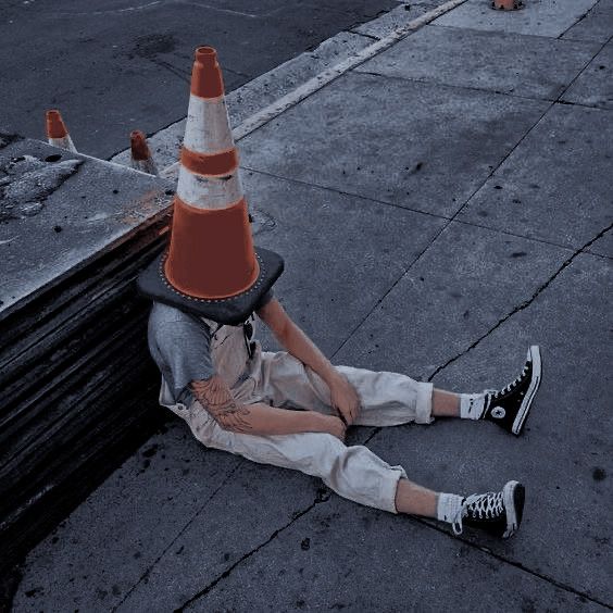 a person laying on the ground next to an orange traffic cone