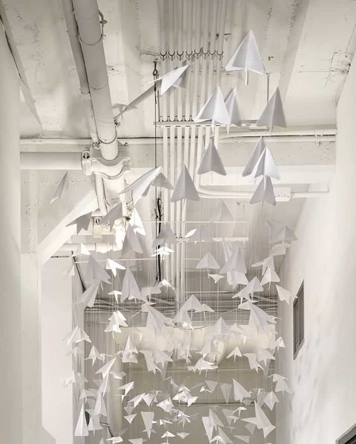 a room filled with lots of white paper cranes hanging from the ceiling and on the walls