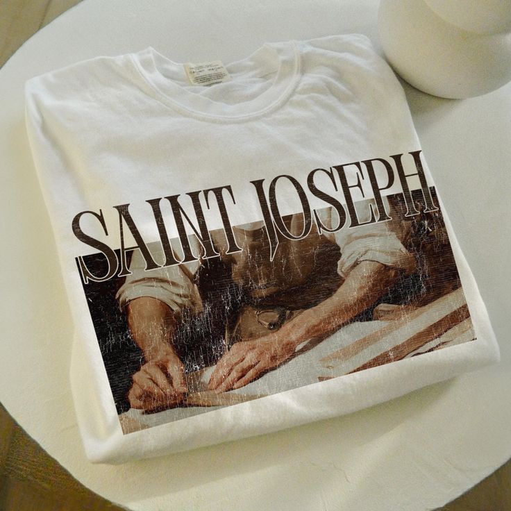 This "Saint Joseph" vintage graphic tee blends faith and style, featuring a classic design perfect for any Catholic wardrobe. Whether for baptisms, first holy communion, or as a confirmation gift, this shirt honors Saint Joseph, the father of Jesus. It's also an ideal gift for godfathers or anyone devoted to their faith. With its timeless, vintage aesthetic, this tee makes a unique and thoughtful addition to any believer's wardrobe. Show your love for Saint Joseph in a way that's both fashionabl Vintage Christian Tshirt, Catholic St Joesph Tshirts, Catholic Fashion, Community Shirt, Catholic Shirt, Catholic Tshirts, Saints Shirts, Aesthetic Tshirt, Spiritual Clothing