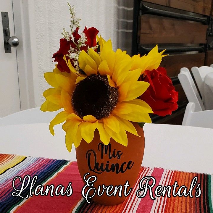 a vase with sunflowers and other flowers on top of a table that says miss quince