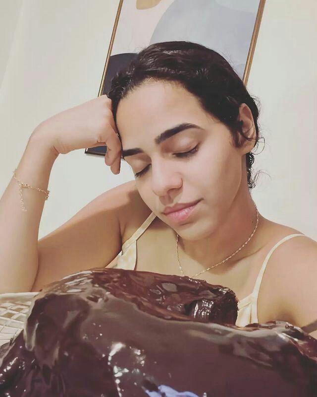 a woman sitting in front of a chocolate cake