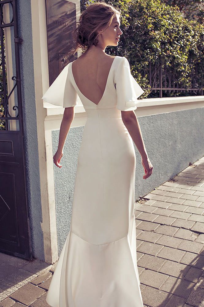 a woman in a white wedding dress walking down the street with her back to the camera