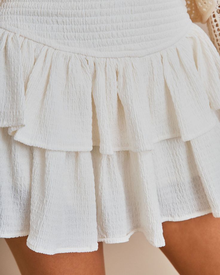 Best Seller Fit & Flowy Shellââ‚?5% Polyester and 5% Spandex and Liningââ‚?100% Rayon Hand Wash Cold. Dry Flat Mini Length Smocked Waistband Tiered Skirt No Closures Fully Lined //Best Seller//Show off your legs in the Queensland Smocked Ruffle Mini Skirt in white that features dramatic ruffles.Styled with: Shelly Sweater and Dev Bootie. ---SIZE AND FIT---Model is Wearing a Size Small. Height is 5'7"". Bust is 32ââ‚? Waist 25ââ‚? and Hips 30ââ‚?/span> Size XS: Length measures 13.5ââ‚?from waist to hem with a 20ââ‚?waist and a 25ââ‚?hip Size S: Length measures 14ââ‚?from waist to hem with a 22ââ‚?waist and a 26ââ‚?hip Size M: Length measures 15ââ‚?from waist to hem with a 24ââ‚?waist and a 27ââ‚?hip Size L: Length measures 15ââ‚?from waist to hem with a 26ââ‚?waist and a 28ââ‚?hip Need Addi White Tiered Bottoms For Day Out, Spring White Bottoms With Smocked Back, Fitted Bottoms With Smocked Bodice And Tiered Skirt, Spring Tiered Stretch Bottoms, White Fitted Bottoms With Smocked Bodice, Fitted Tiered Mini Skirt With Elastic Waistband, Fitted Bottoms With Smocked Bodice, Mini Length, Fitted Mini Bottoms With Smocked Bodice, White Cotton Bottoms With Smocked Back