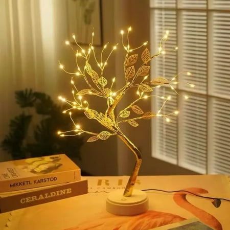 a lighted tree on a table next to some books