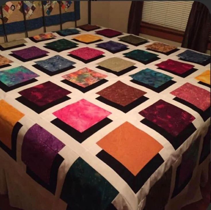 a bed with a colorful quilt on top of it