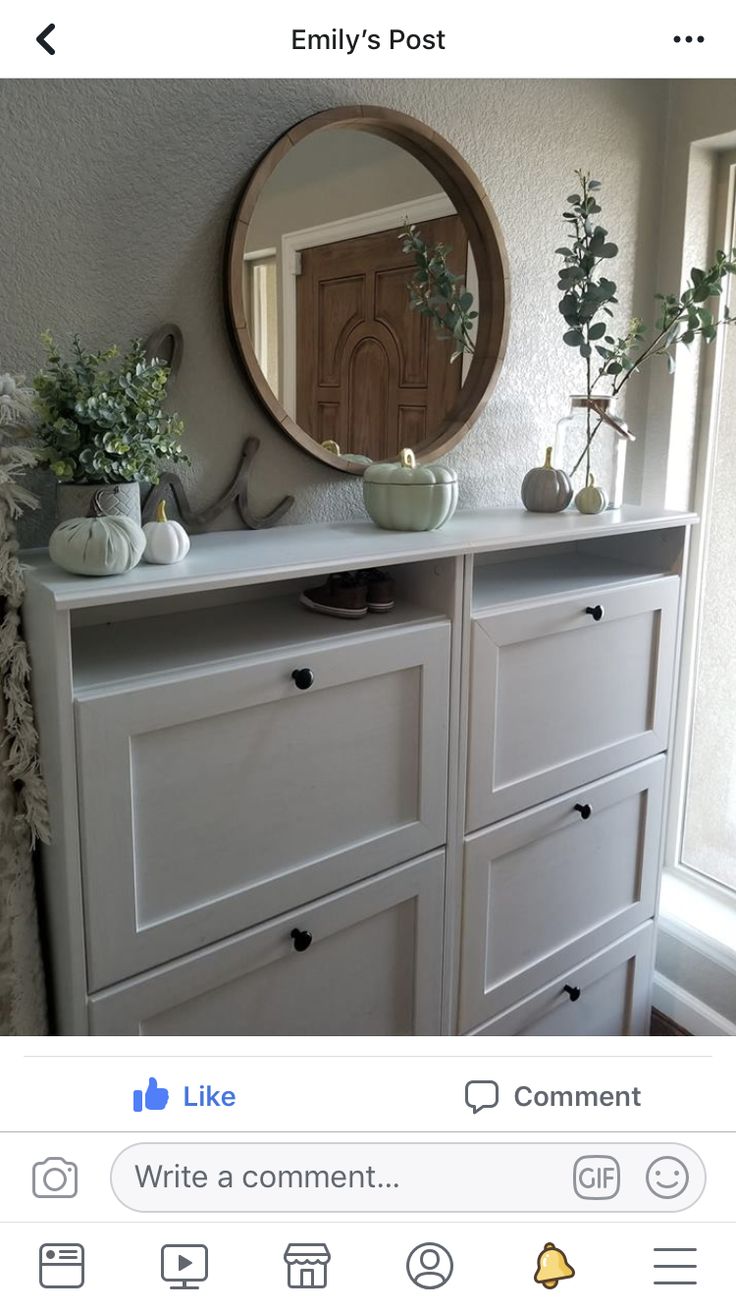 a white dresser with plants on top and a mirror above it