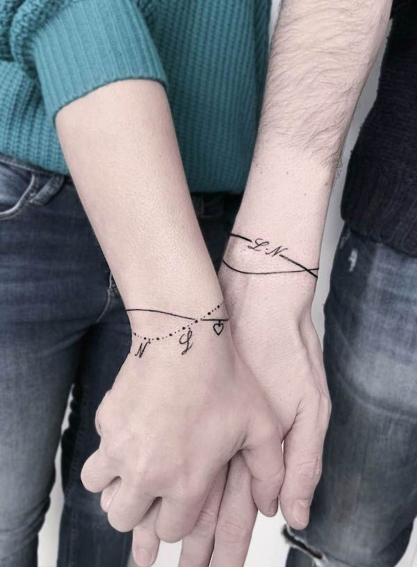 two people holding hands with tattoos on their wrist and one is holding the other's hand