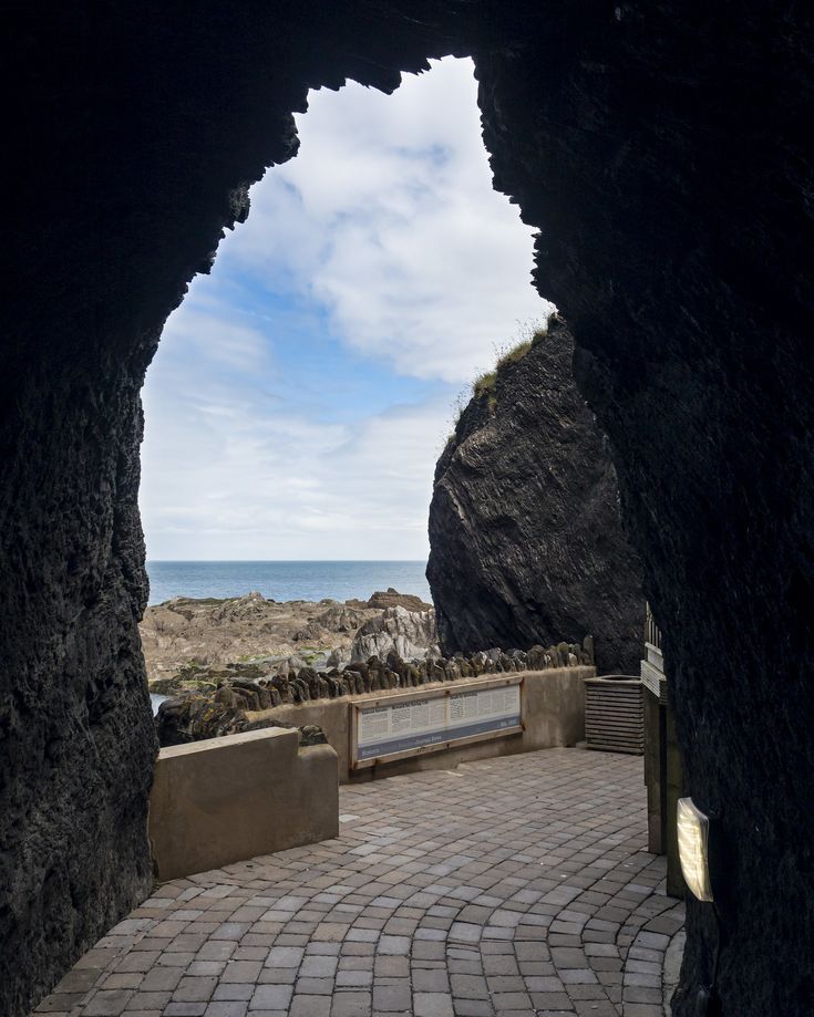 an archway leading to the ocean with a bench in between it and a stone walkway