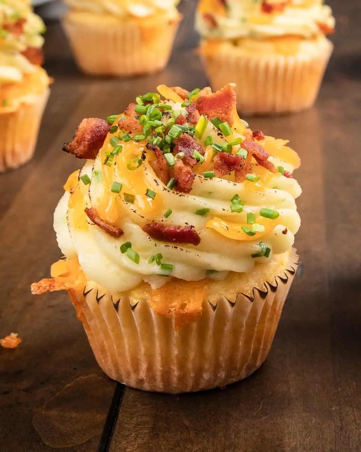 several cupcakes with bacon and green toppings on them sitting on a table