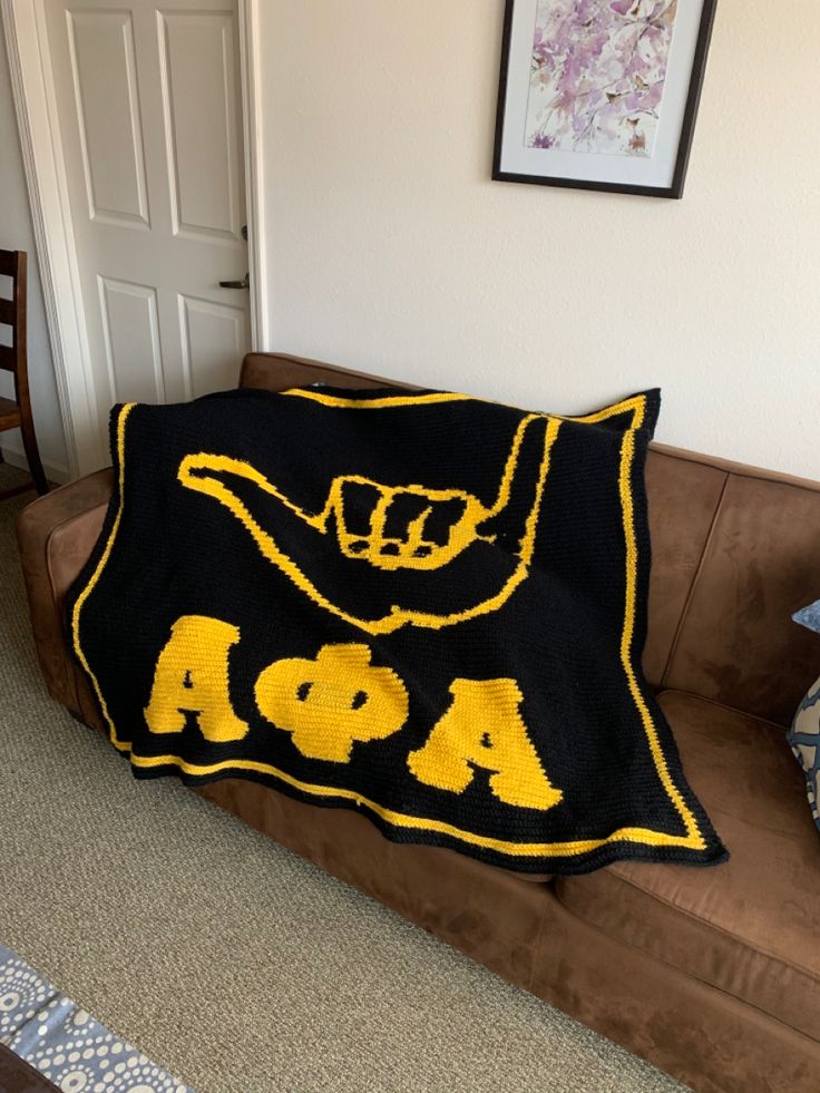 a couch with a blanket on it that has the letters aoa written in yellow