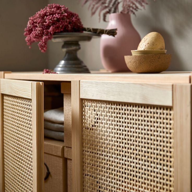 a wooden cabinet with some vases and flowers on top