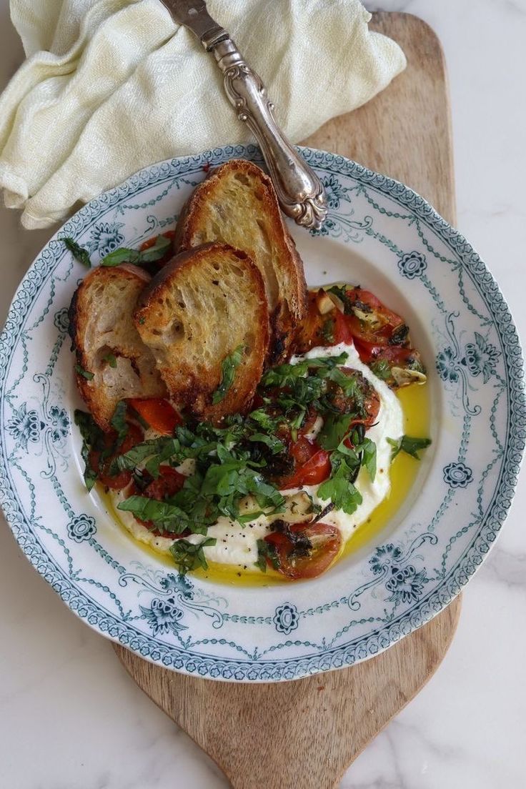 a white and blue plate topped with toasted bread next to a bowl of salad