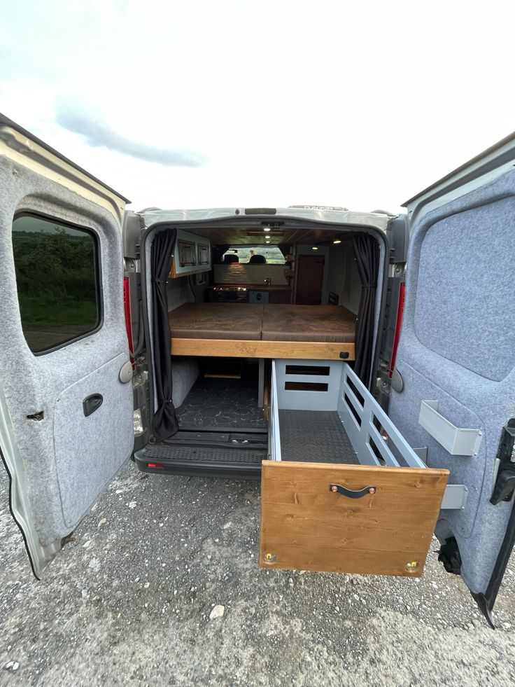 the back end of an empty van with its doors open and drawers opened in front of it