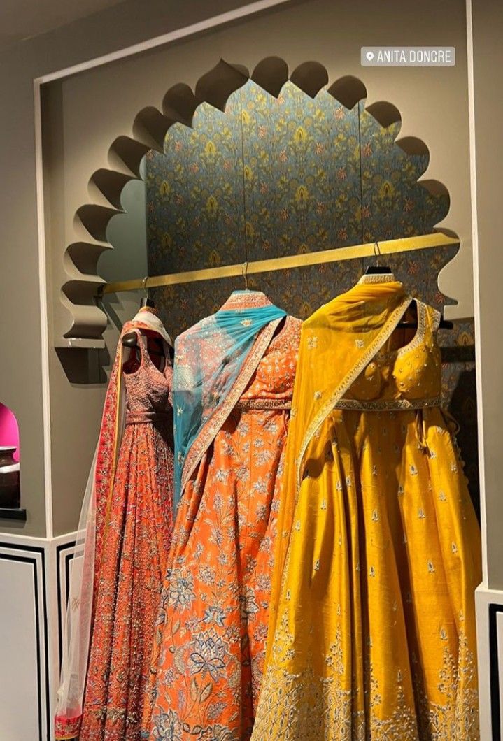 three dresses on display in front of a mirror