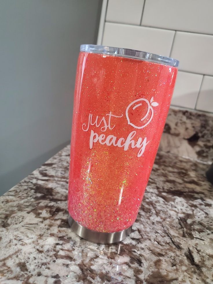 a red tumbler with the words just peachy on it sitting on a counter