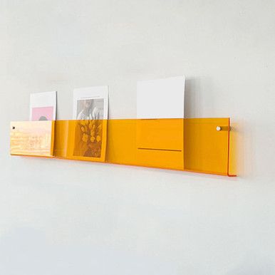 a yellow shelf with three pictures hanging on it's sides and two photos mounted to the wall