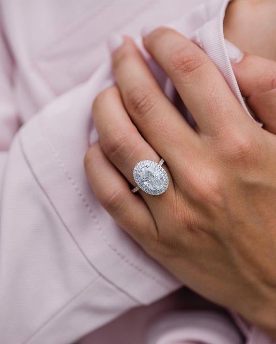 a close up of a person's hand holding an engagement ring