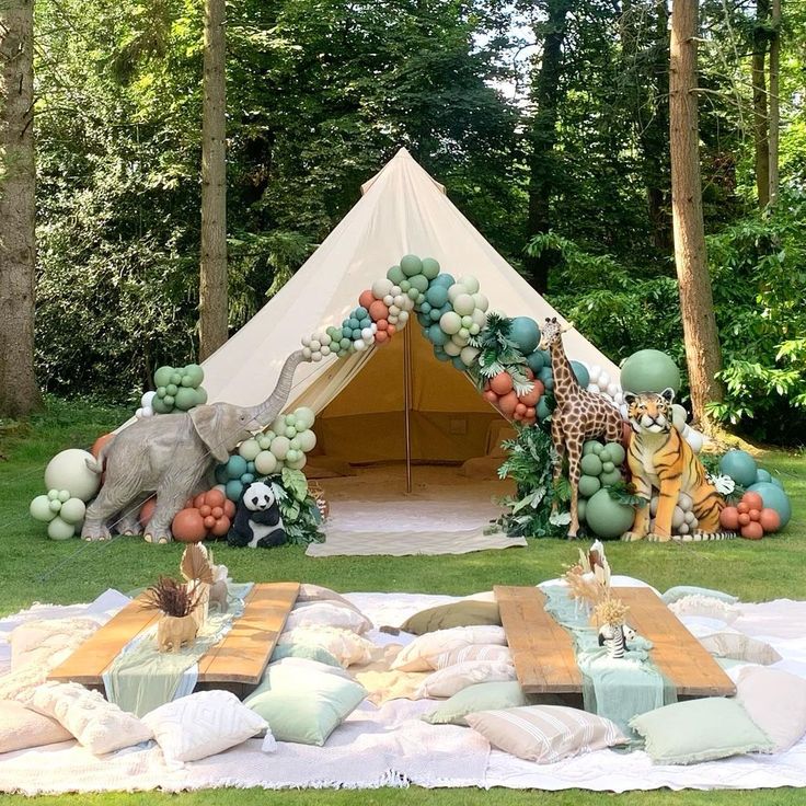 a tent set up in the middle of a forest with balloons and animals on it