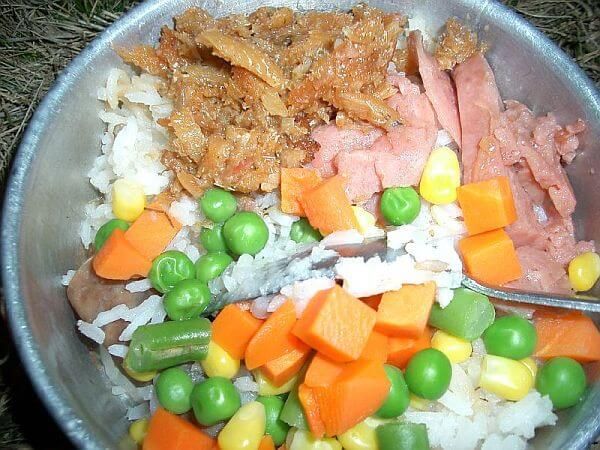 a bowl filled with rice, peas, carrots and other vegetables next to meat