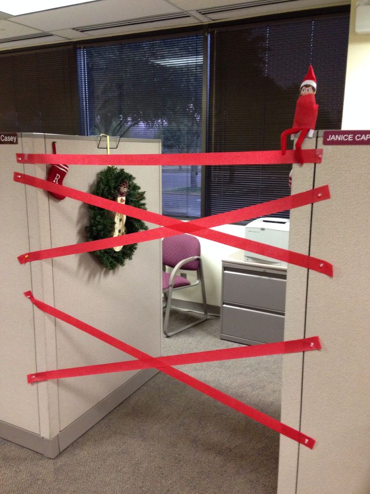 an office cubicle decorated for christmas with red tape and santa's hat on the door