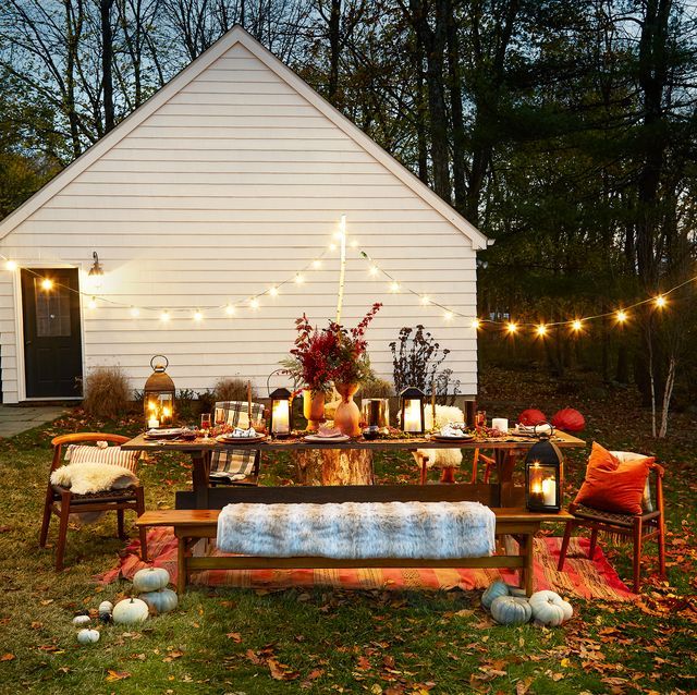 a wooden bench sitting in the middle of a yard with lights strung from it's roof