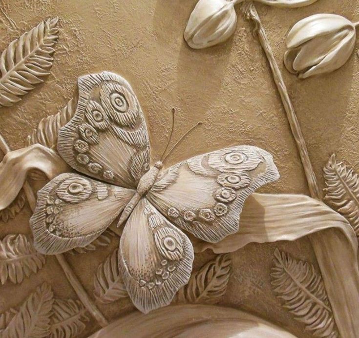 a close up of a carving of a butterfly on a plant with flowers in the background