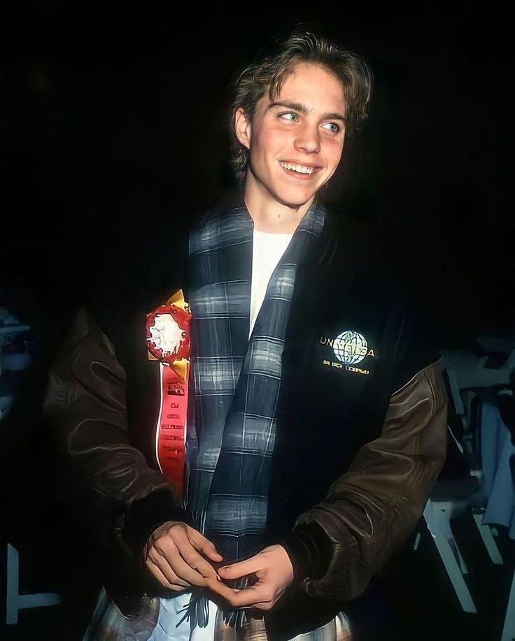 a young man wearing a jacket and scarf