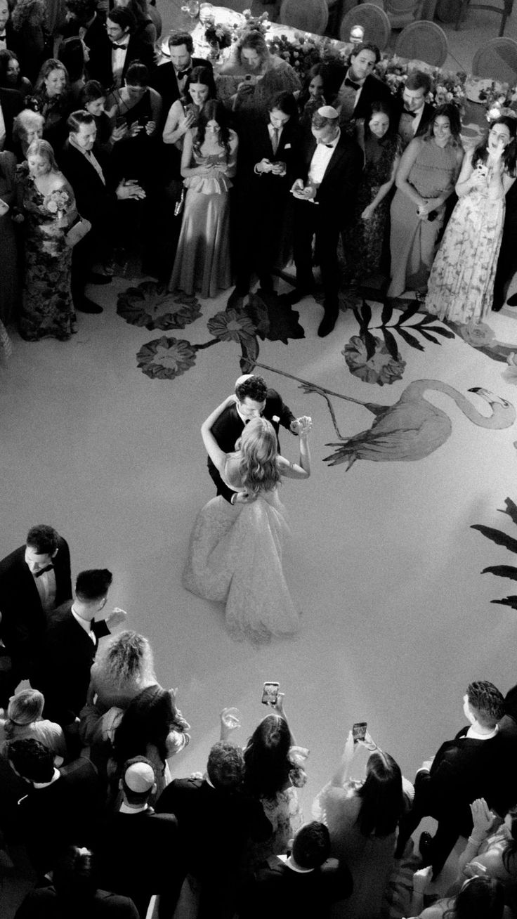 a black and white photo of a bride and groom kissing in front of an audience