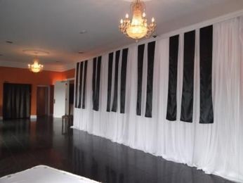 an empty room with black and white drapes on the wall, chandelier hanging from the ceiling