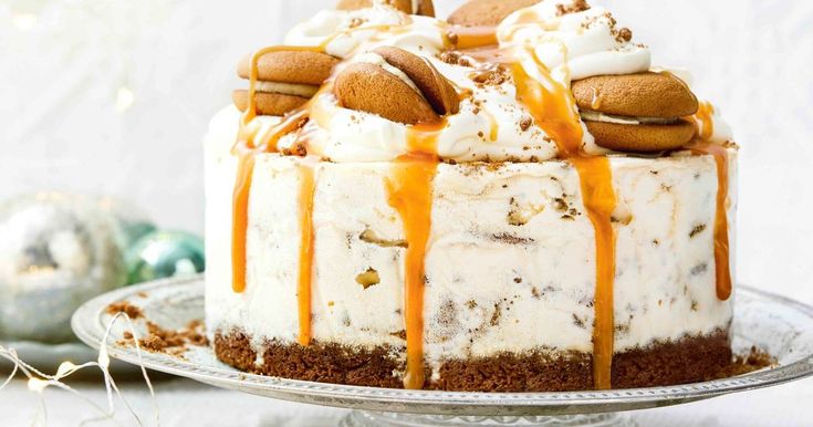 a cake with white frosting and caramel drizzle on top, sitting on a plate