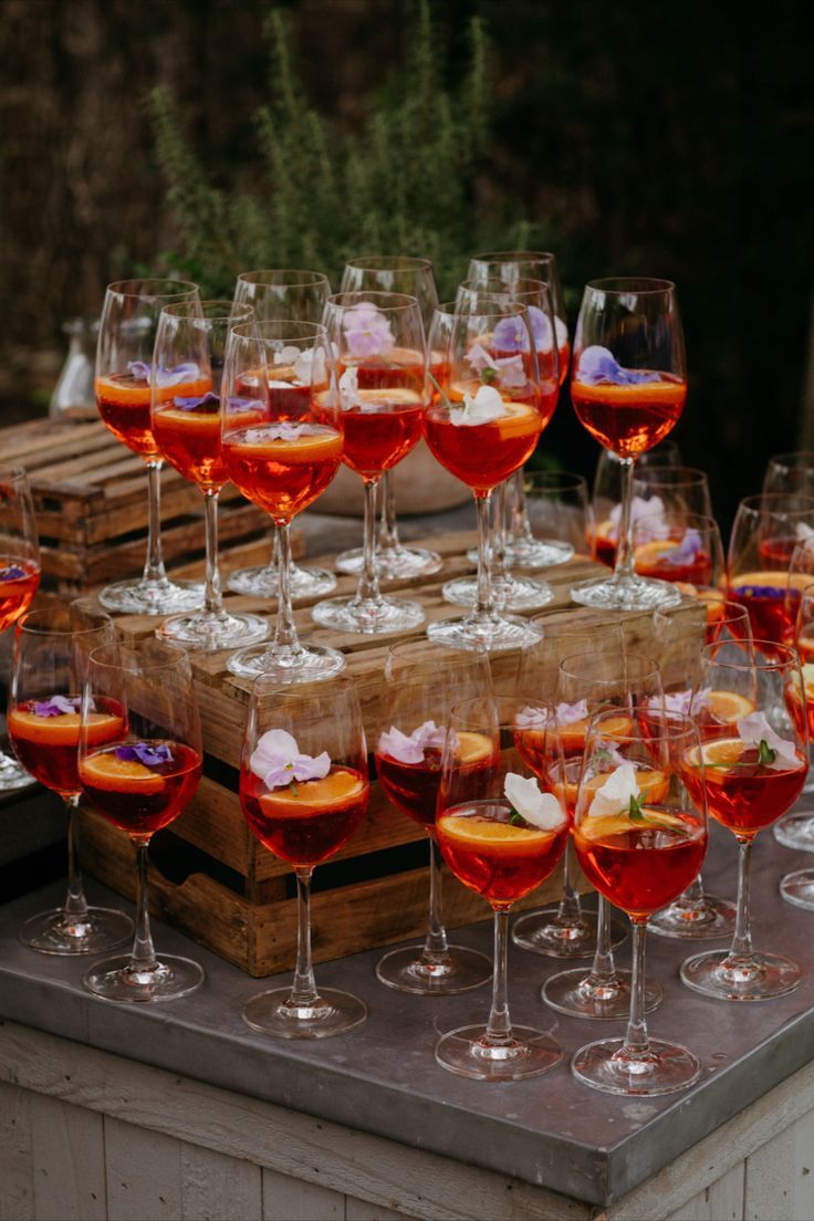 many glasses of wine are lined up on a wooden box with ice cubes in them