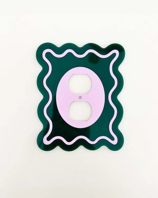 a green and pink light switch plate cover with an o on the bottom in front of a white wall