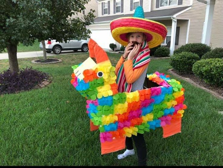 a child wearing a sombrero and holding a pinata horse in front of a house