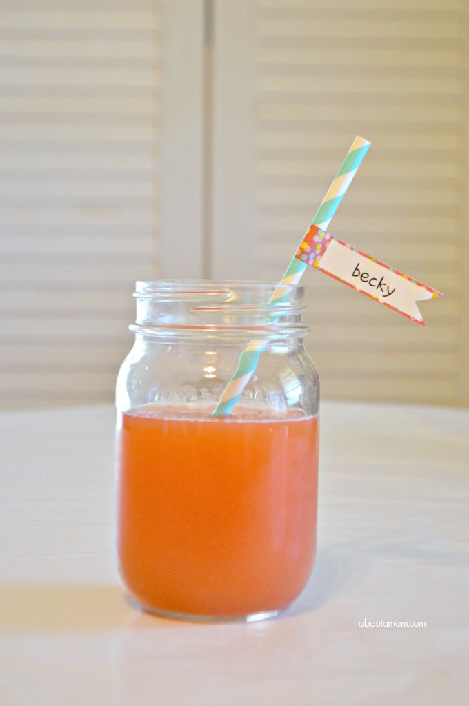 a glass jar filled with orange juice and a striped straw sticking out of the top