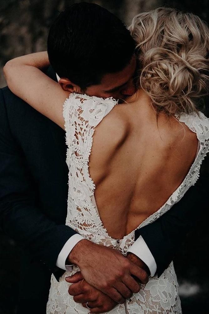 a bride and groom embracing each other in front of a rock wall with their back to the camera