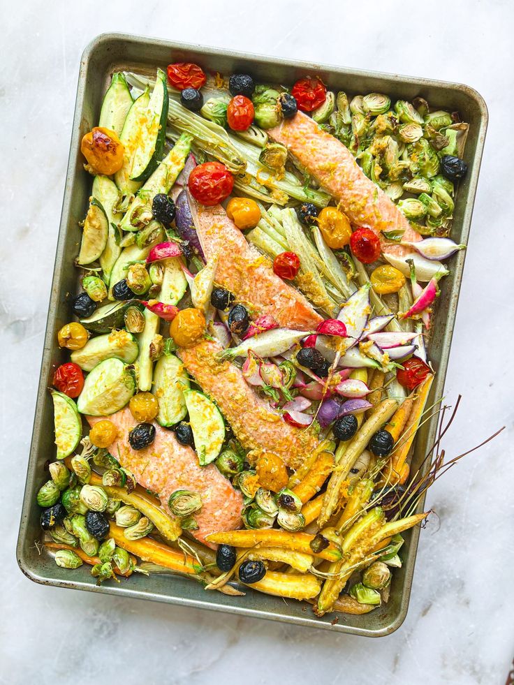 a pan filled with fish and vegetables on top of a table