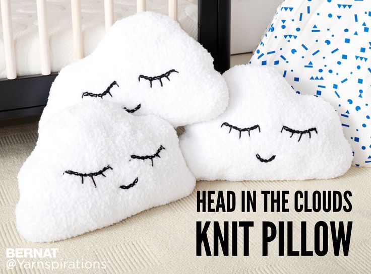 two pillows with eyes drawn on them sitting next to a crib