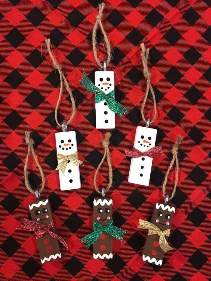 four snowmen are hanging from twine on a red and black checkered tablecloth