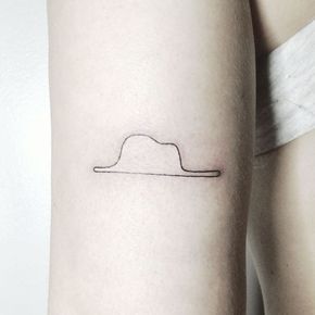 a woman's arm with a small hat tattoo on the left side of her leg