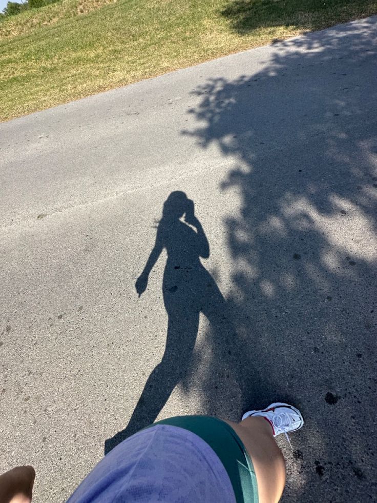 the shadow of a person standing in front of a skateboarder on the street