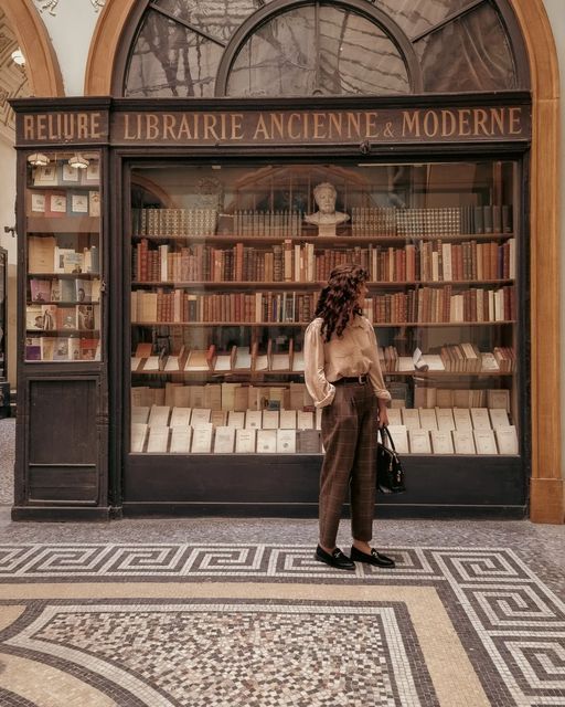 a woman standing in front of a book store with lots of books on the shelves