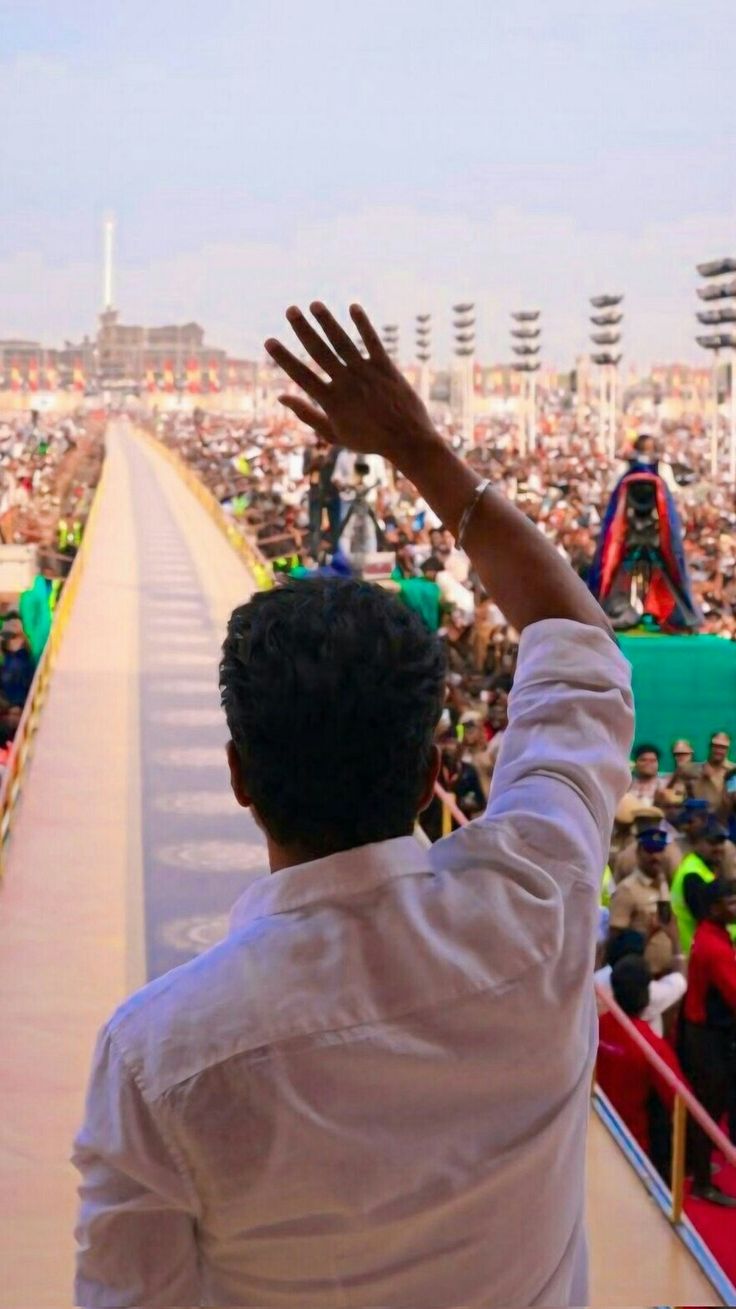 a man is standing in front of a crowd with his hands up to the sky