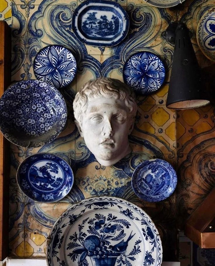 blue and white plates are on display in front of a wall with an image of a man's head