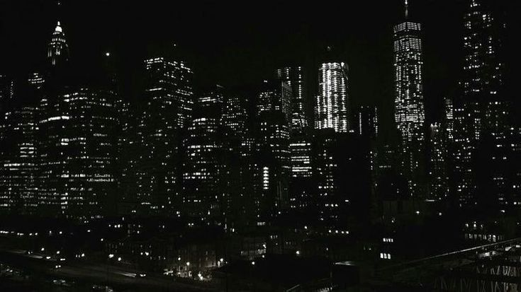 black and white photograph of the city at night with skyscrapers lit up in the background